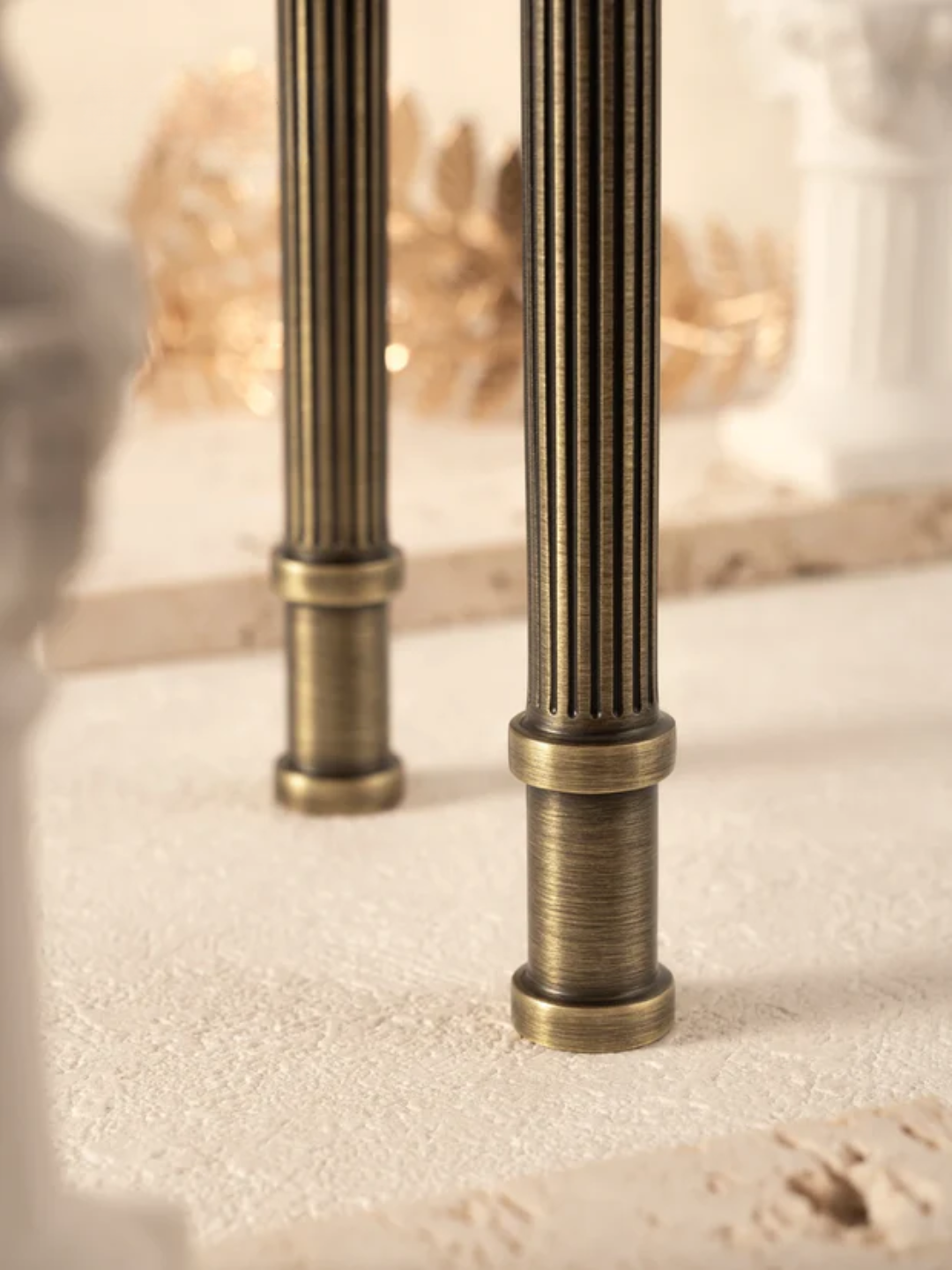 Close-up of two brass columns on a textured surface with a blurred background