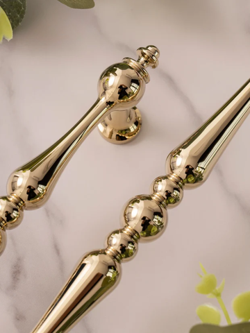 Gold decorative elements on a marble surface with green leaves.