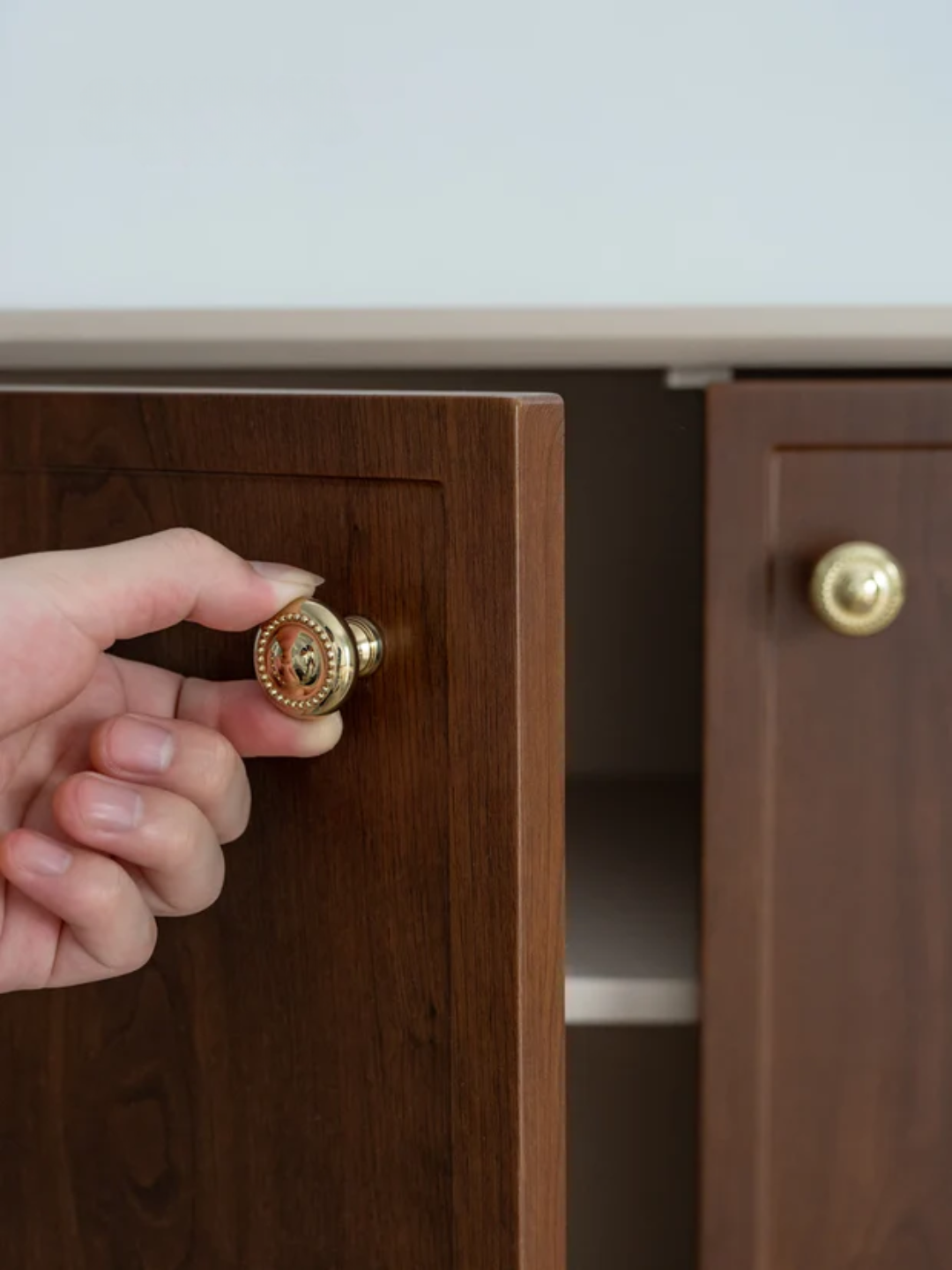 Hand opening a wooden cabinet door with a gold handle, featuring the Santaya brand.