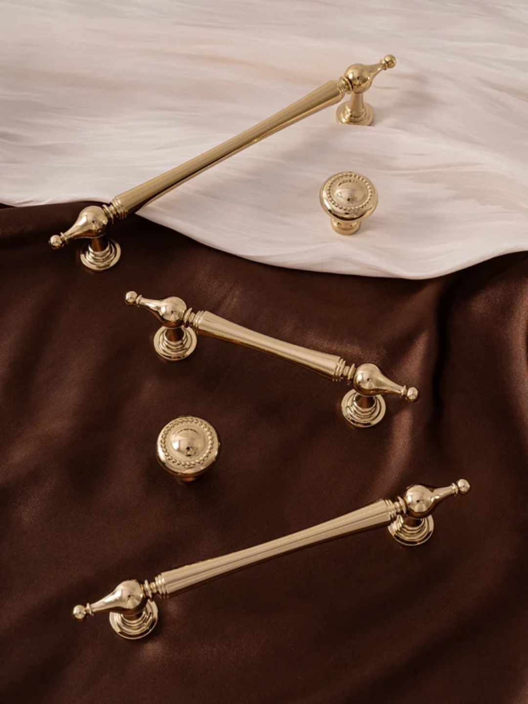 Gold cabinet handles and knobs on a brown and white fabric background