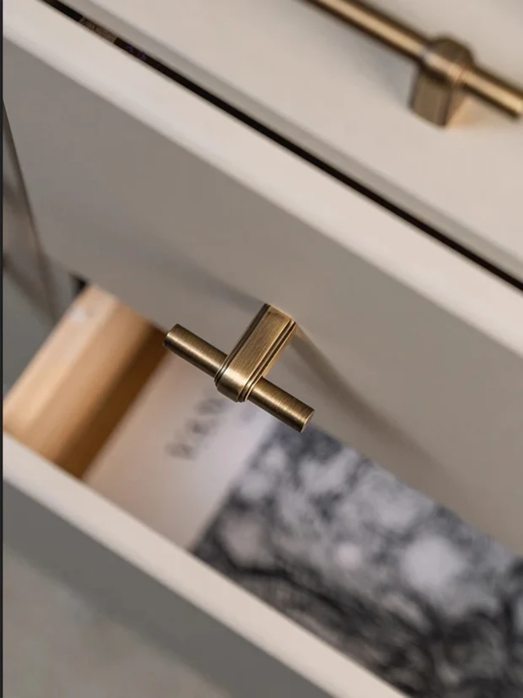Close-up of a drawer with gold handles on a neutral background