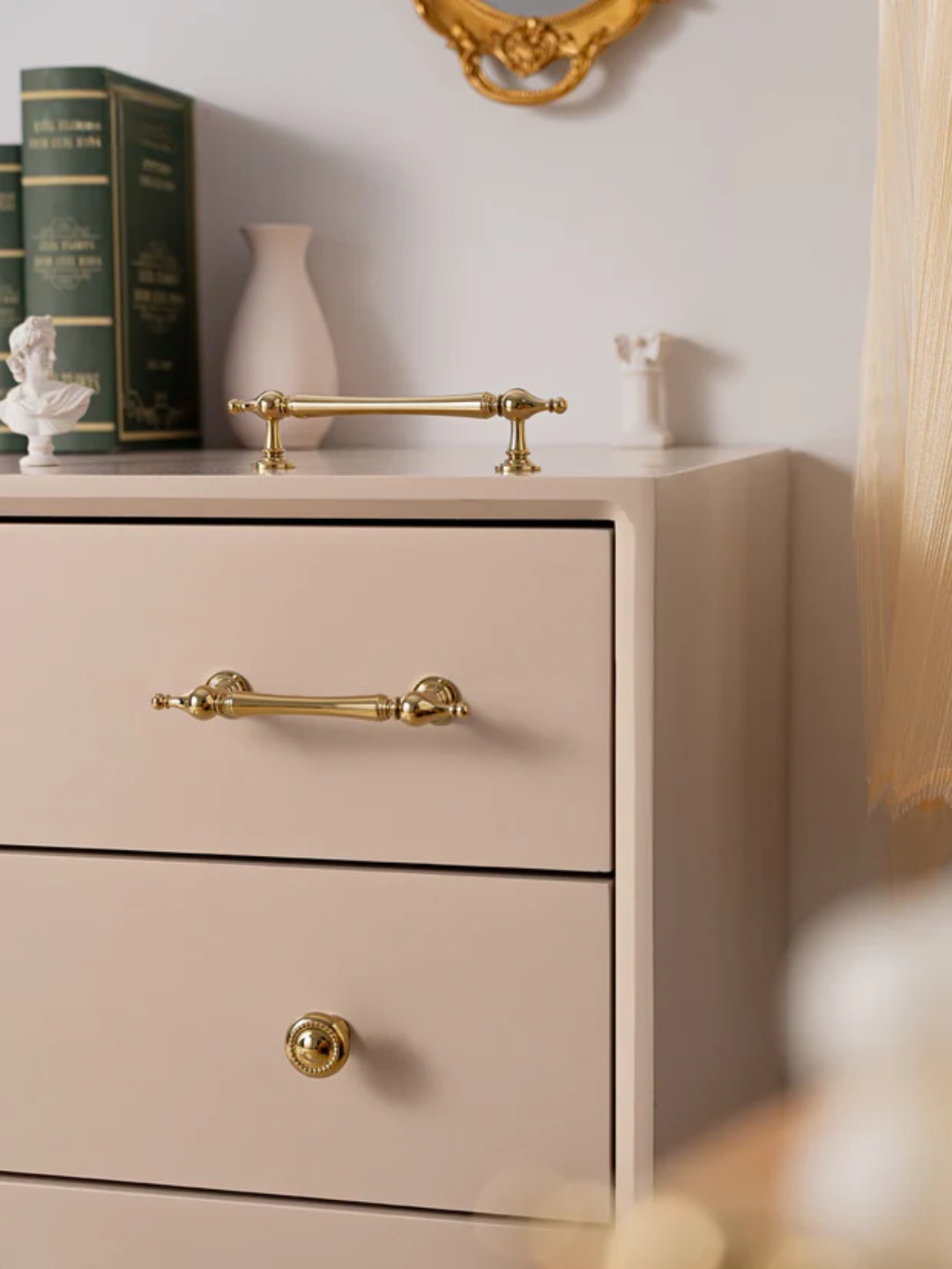 Beige dresser with gold handles and decorative items on top