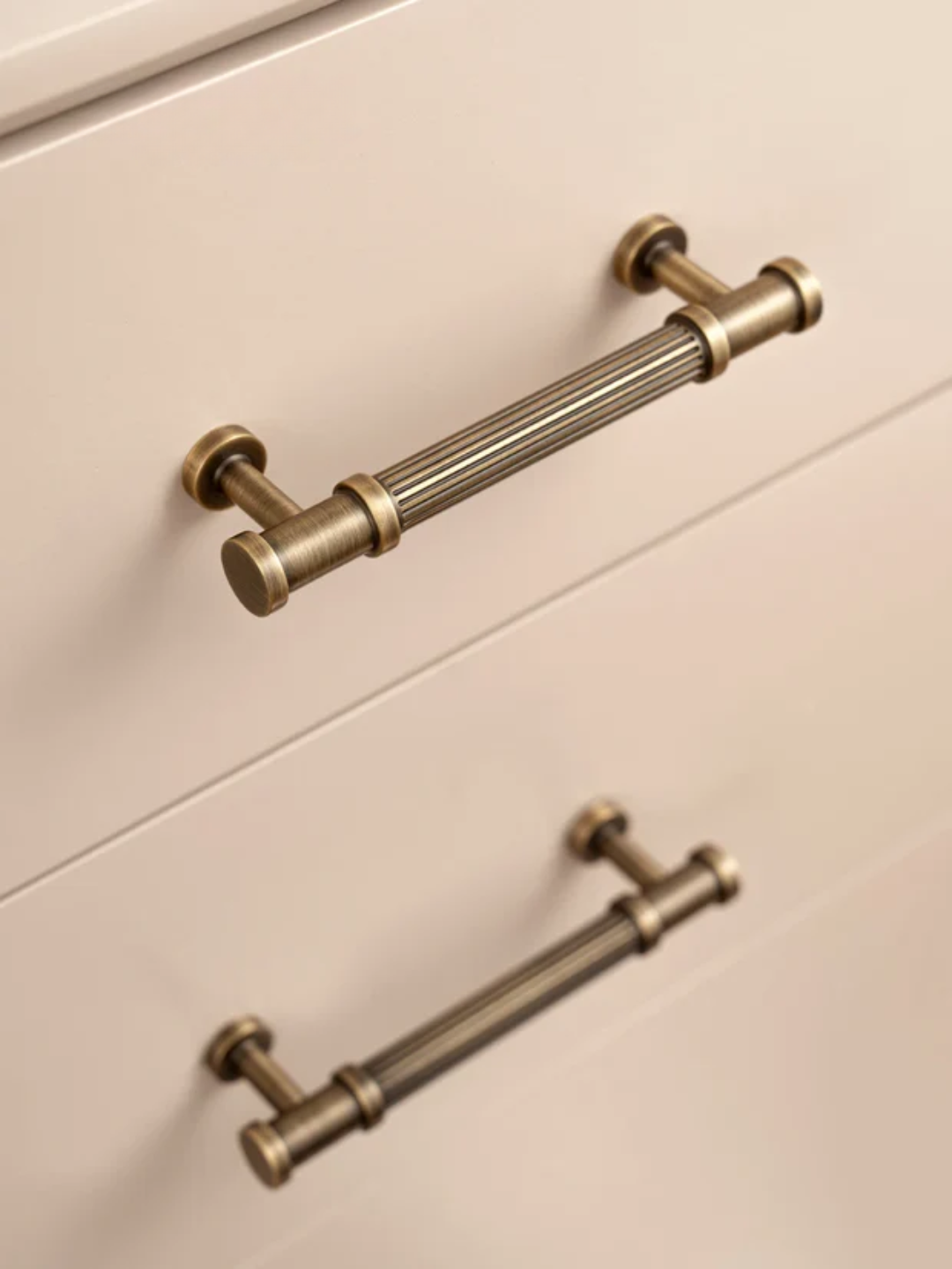 Brass cabinet handles on a light-colored wooden drawer