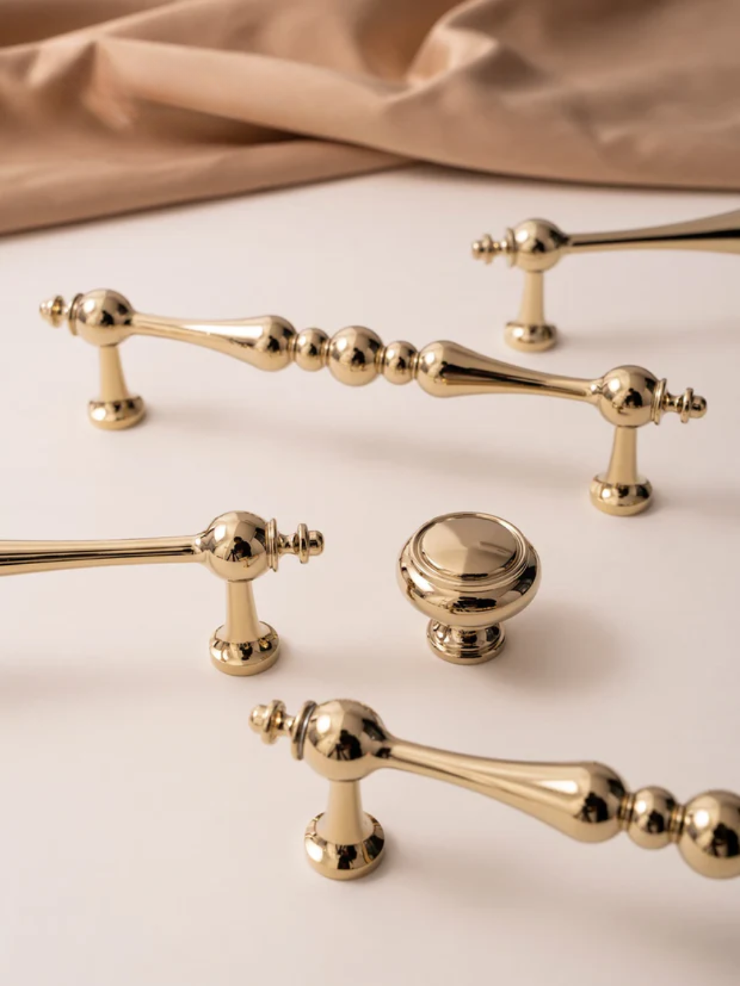 Collection of gold cabinet handles and knobs on a beige background