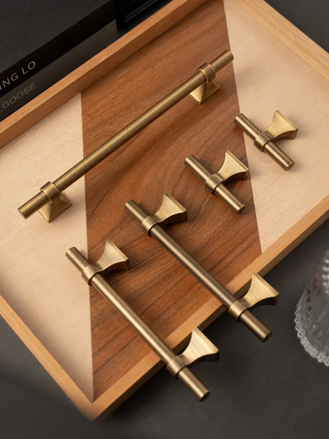 Set of gold cabinet handles displayed on a wooden tray