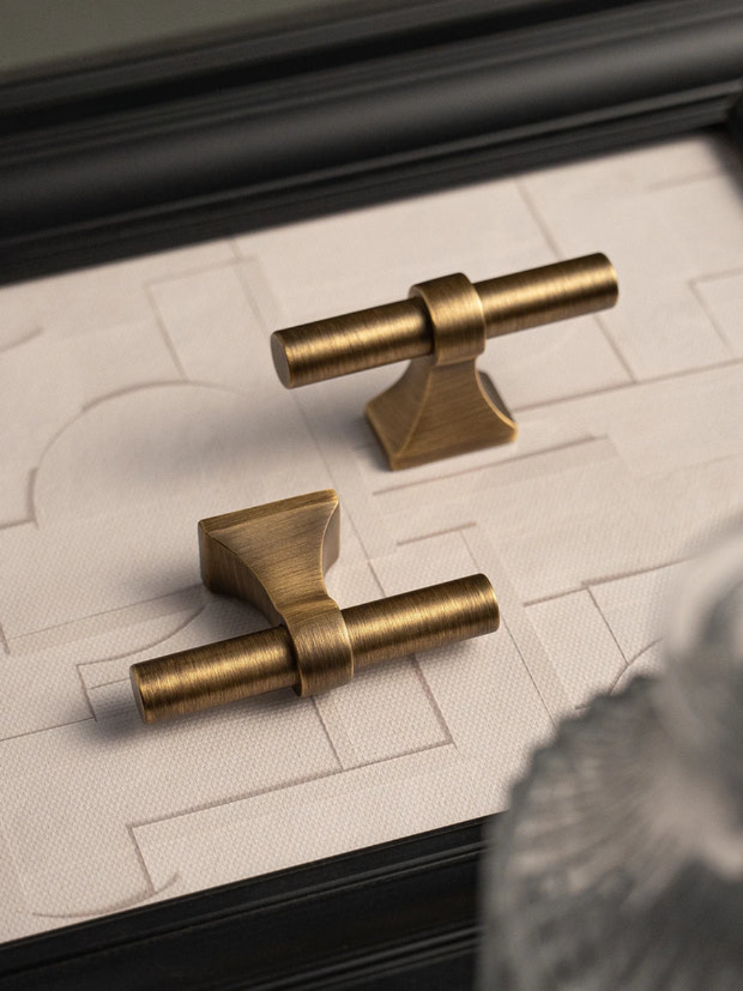 Two gold cabinet handles on a textured surface with a blurred background