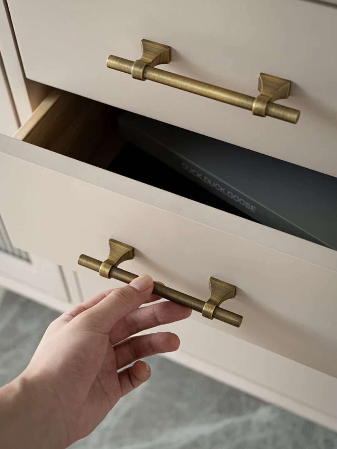 Hand opening a cabinet with brass handles, featuring the Santaya brand.