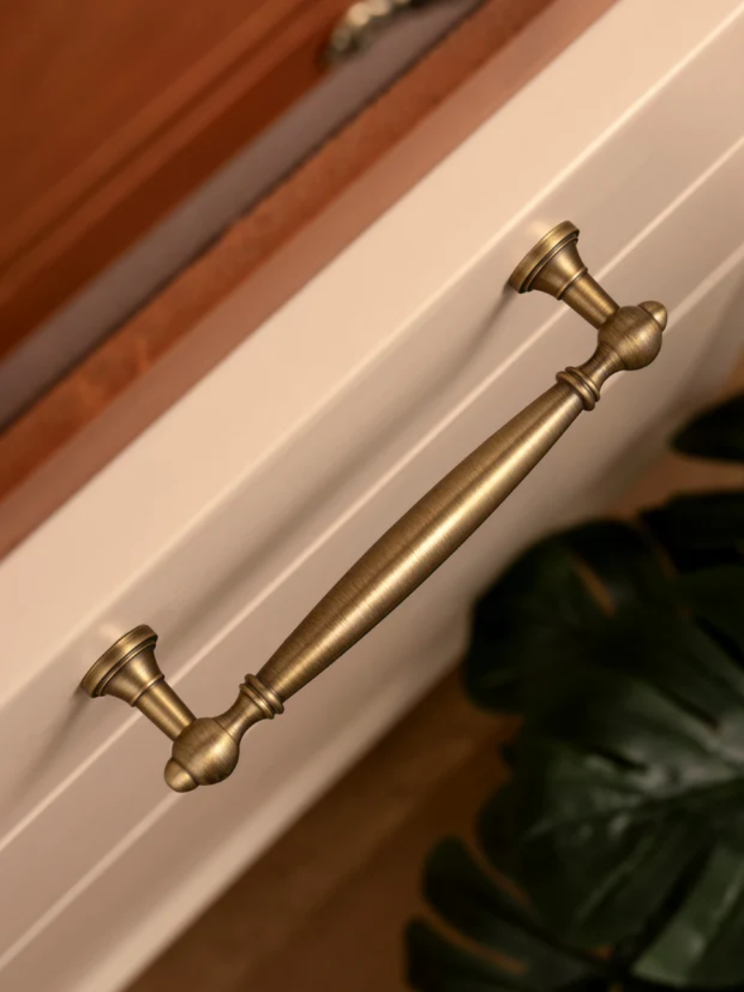 Close-up of a brass cabinet handle on a white drawer