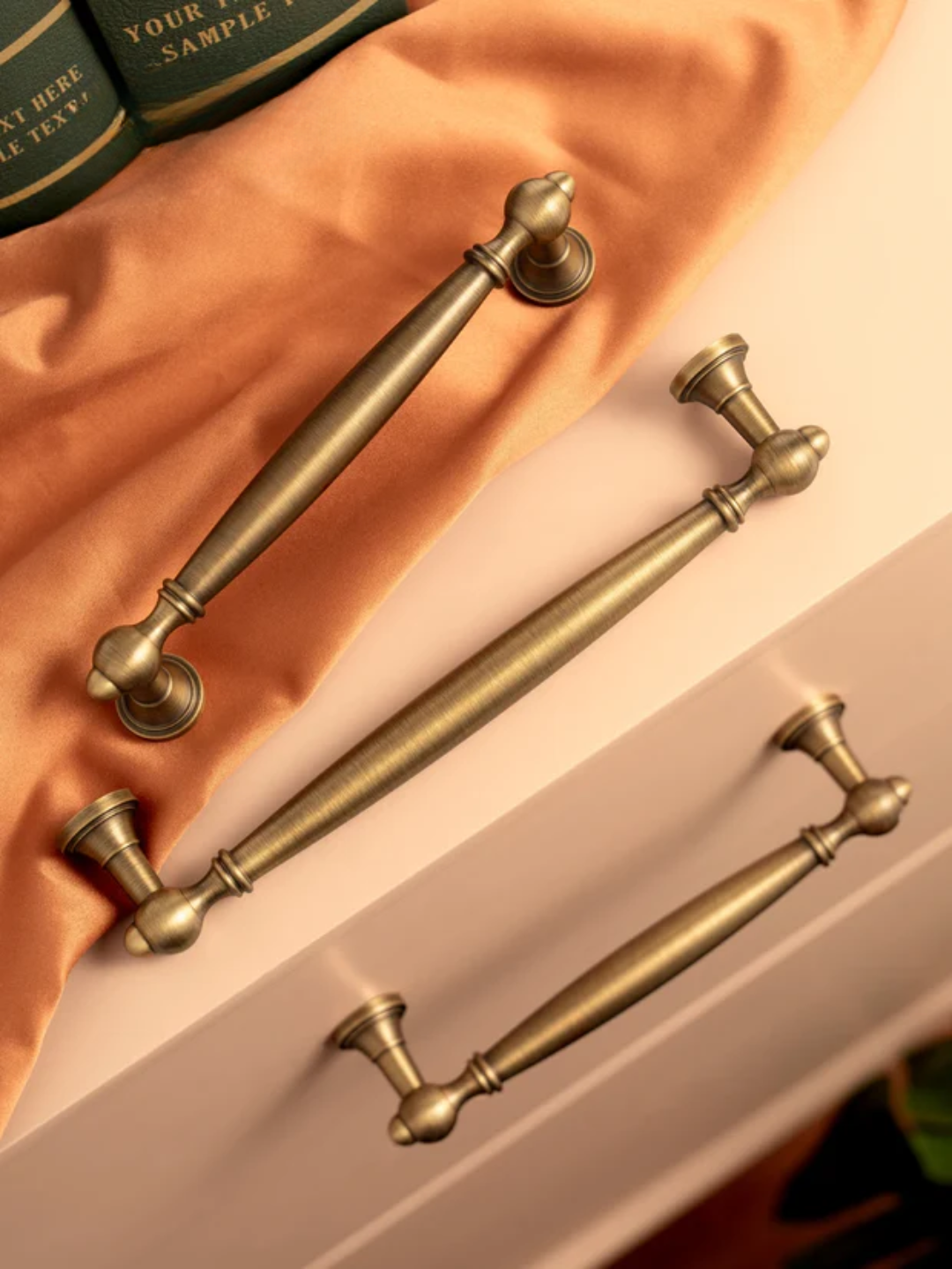 Set of gold cabinet handles on a peach fabric background