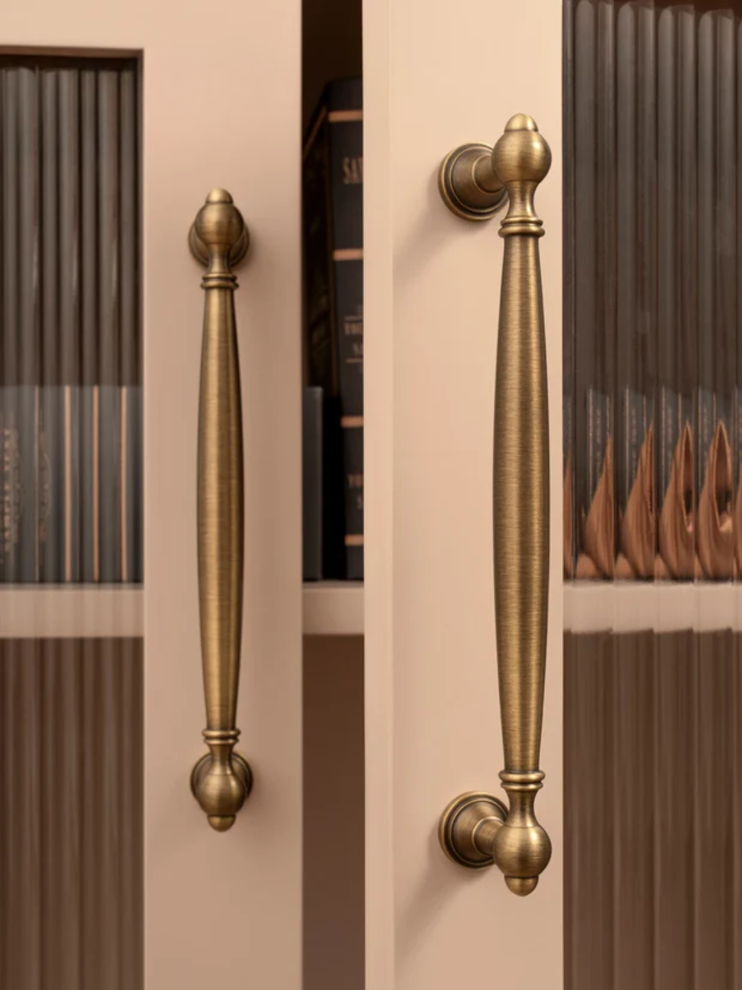 Pair of gold cabinet handles on a door with a striped background