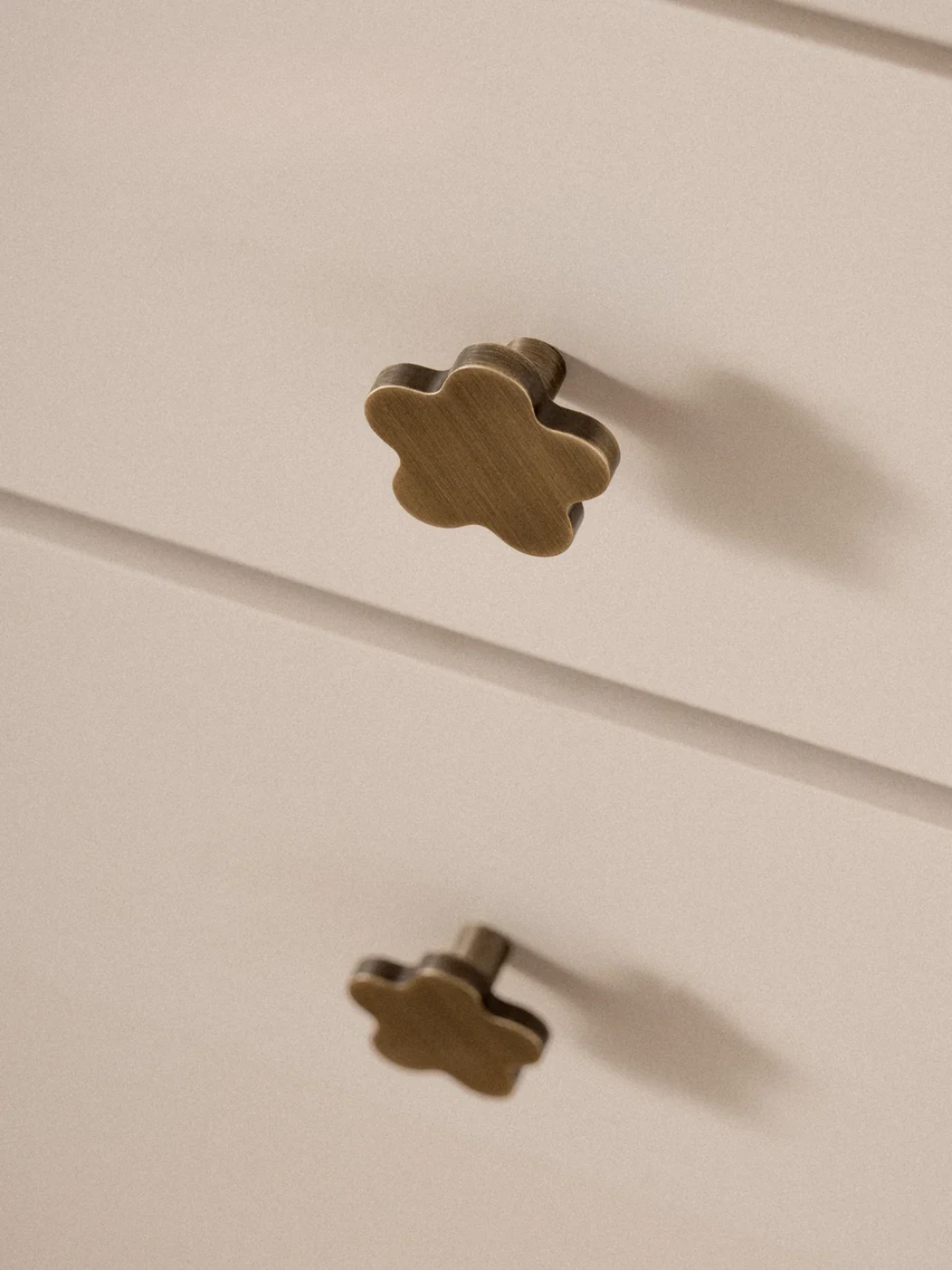 Flower-shaped brass knobs on a beige cabinet.