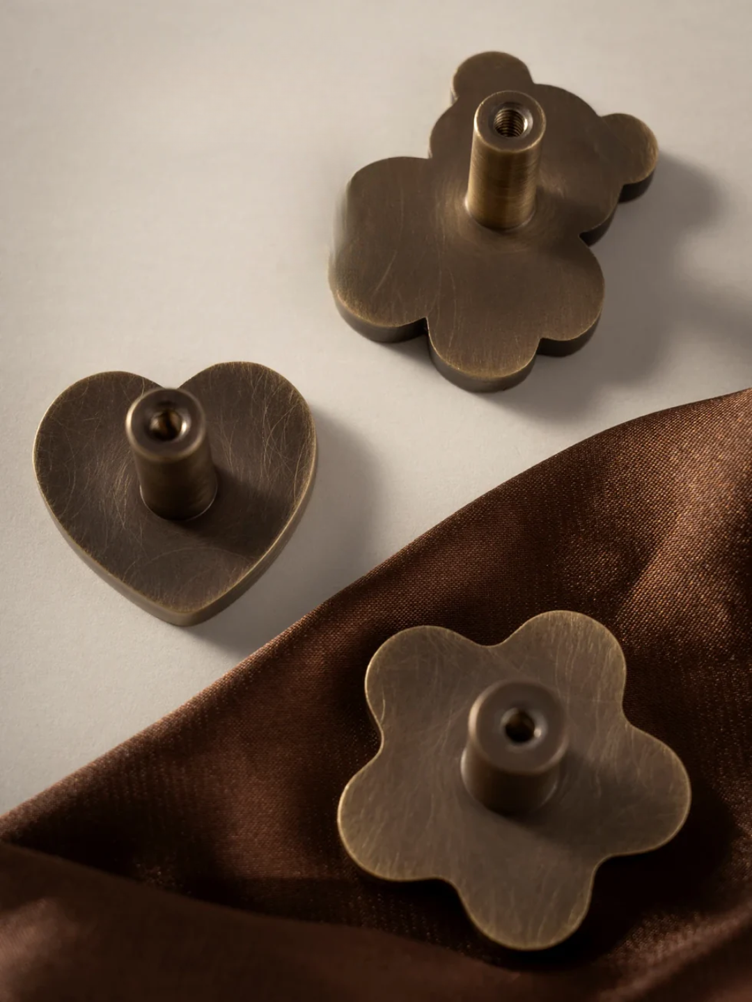 Gold heart and flower-shaped earrings on a brown fabric background