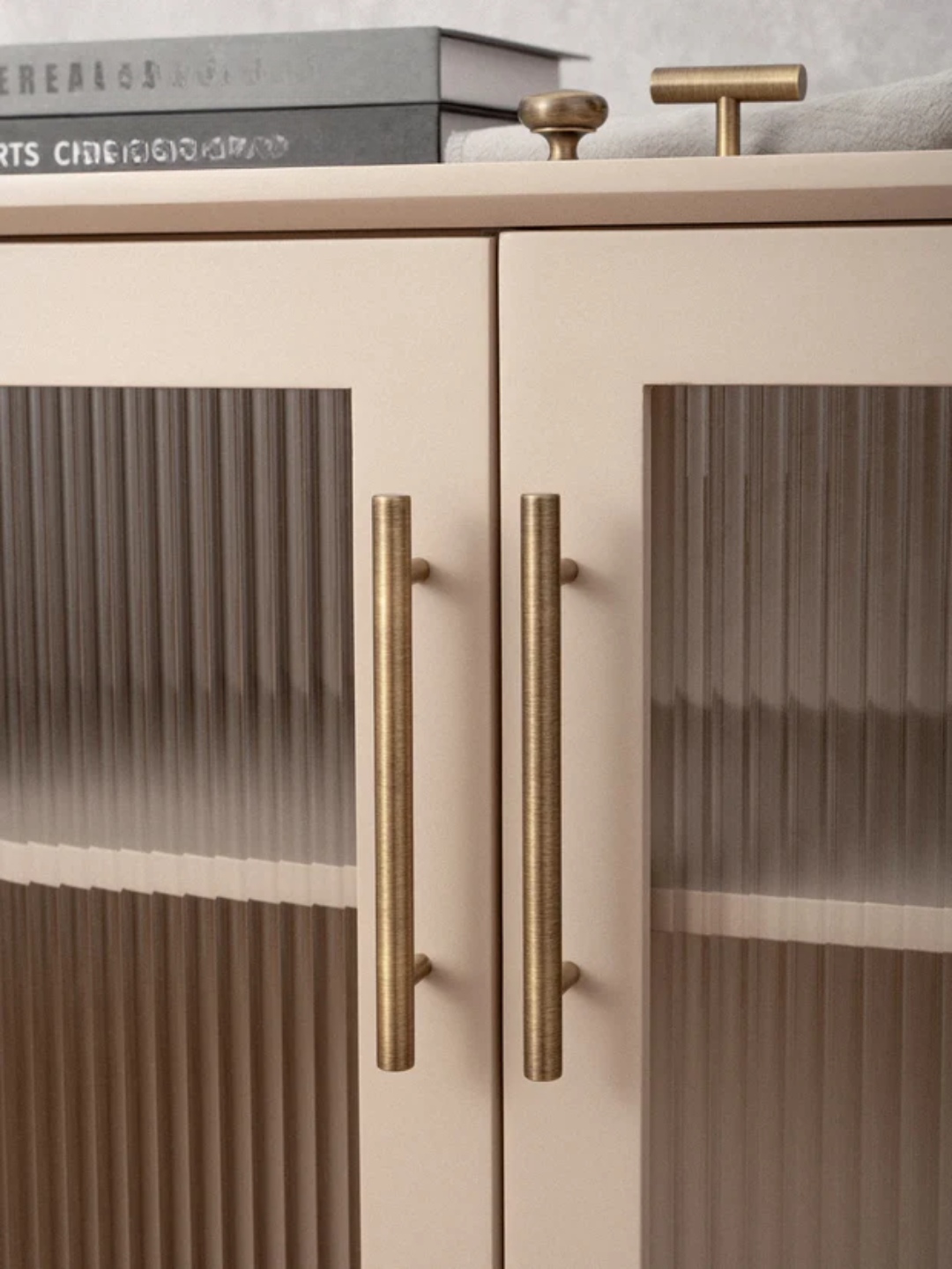 Cabinet with glass doors and brass handles on a neutral background