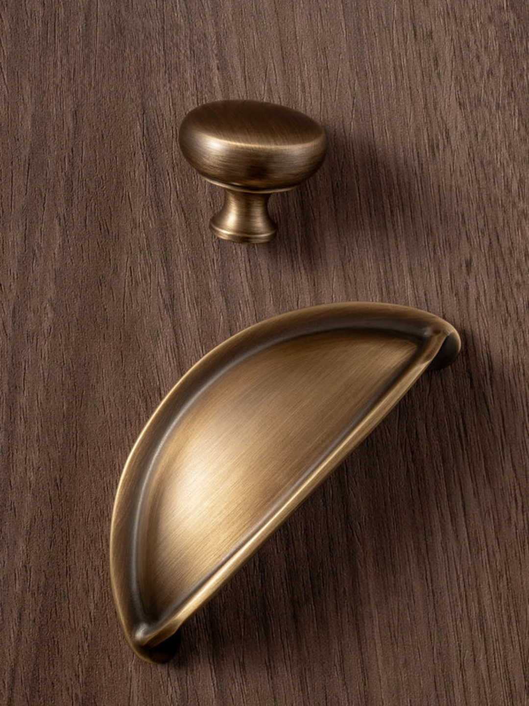 Two brass cabinet handles on a wooden surface