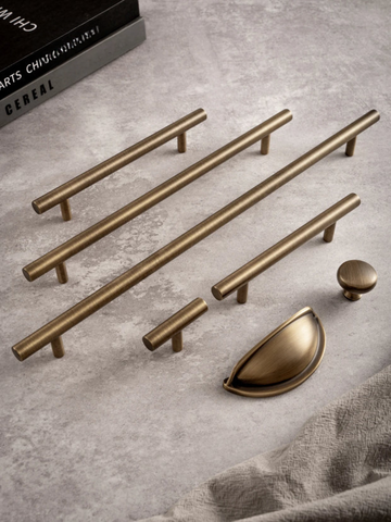 Set of brass cabinet handles and knobs on a gray surface