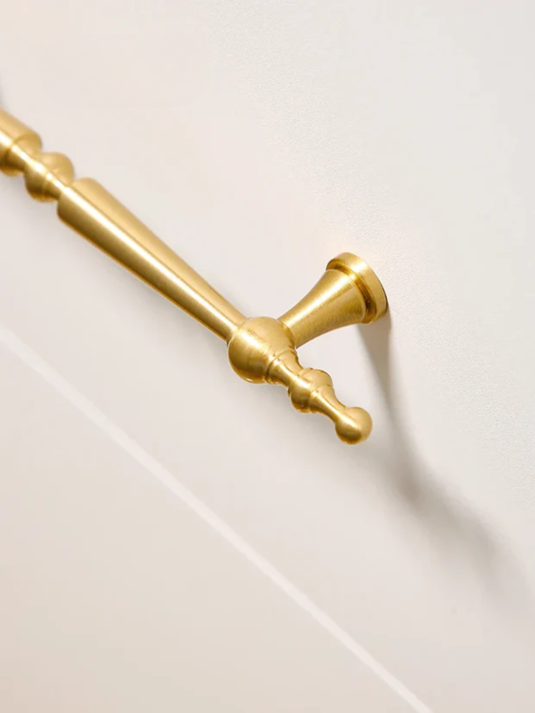 Gold curtain rod on a white tiled wall