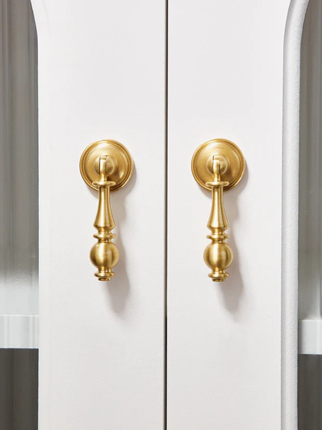 Close-up of a white cabinet with gold handles on a white background