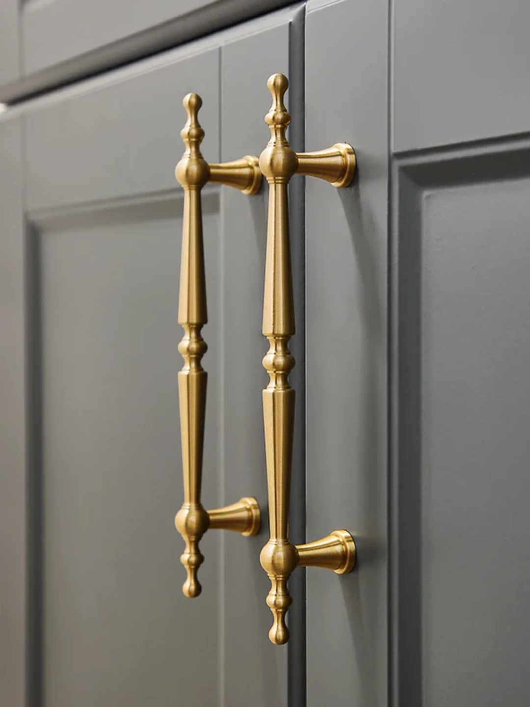 Gold cabinet handle on a gray cabinet door