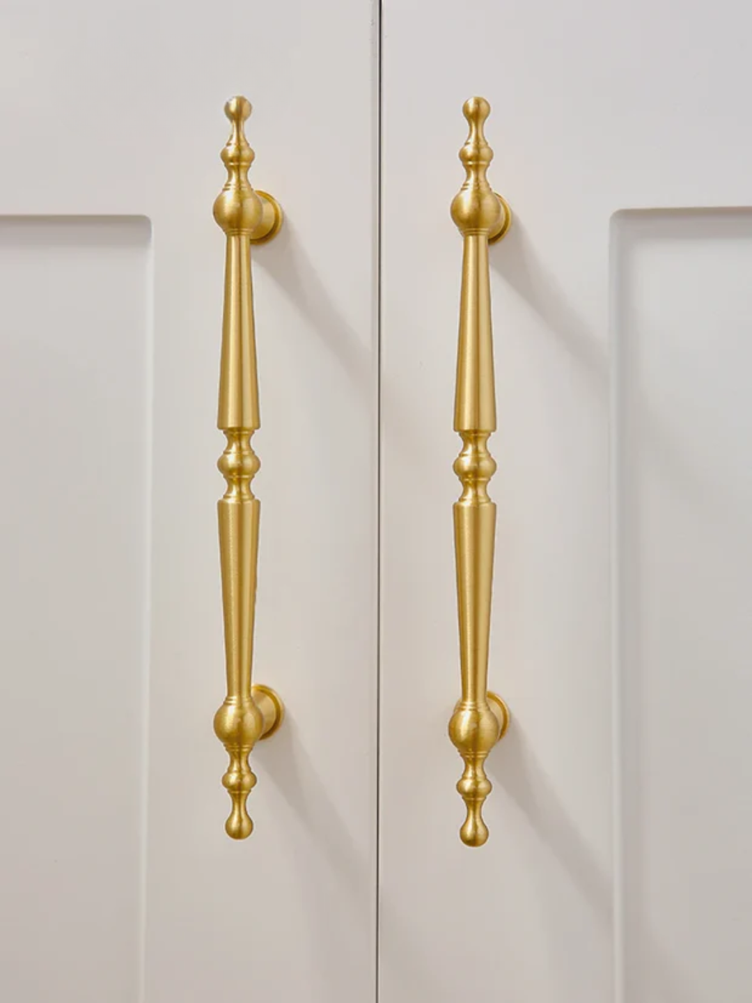 Gold cabinet handles and knobs on a light gray background