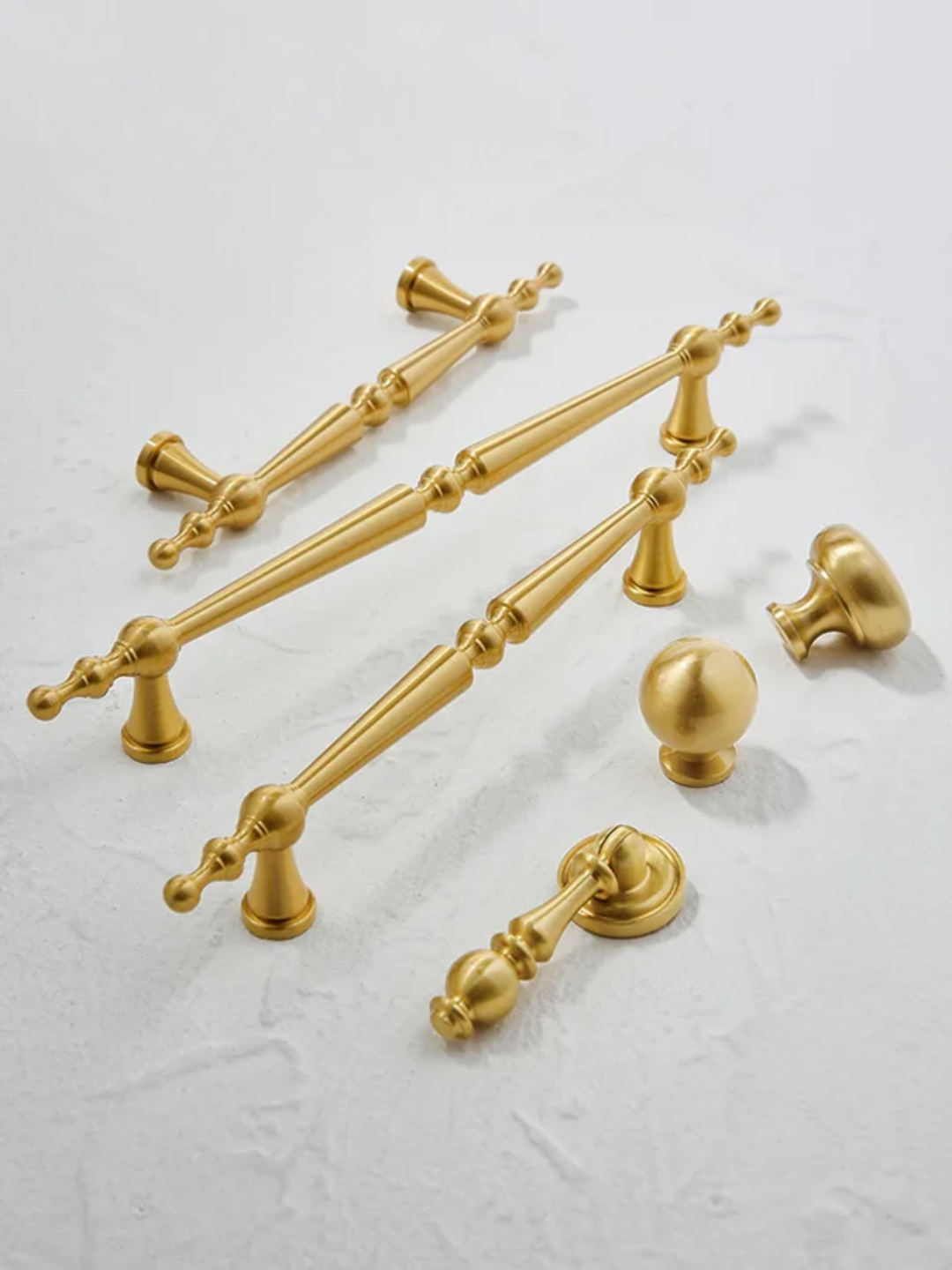 Gold cabinet handles and knobs on a light gray background
