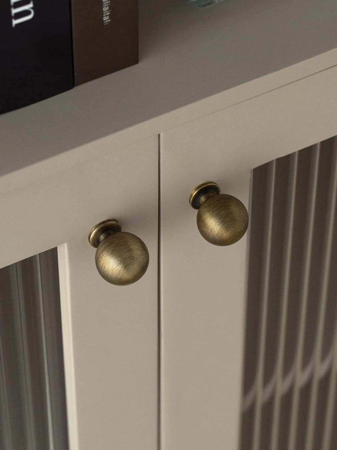 Close-up of a cabinet with brass knobs on a neutral background