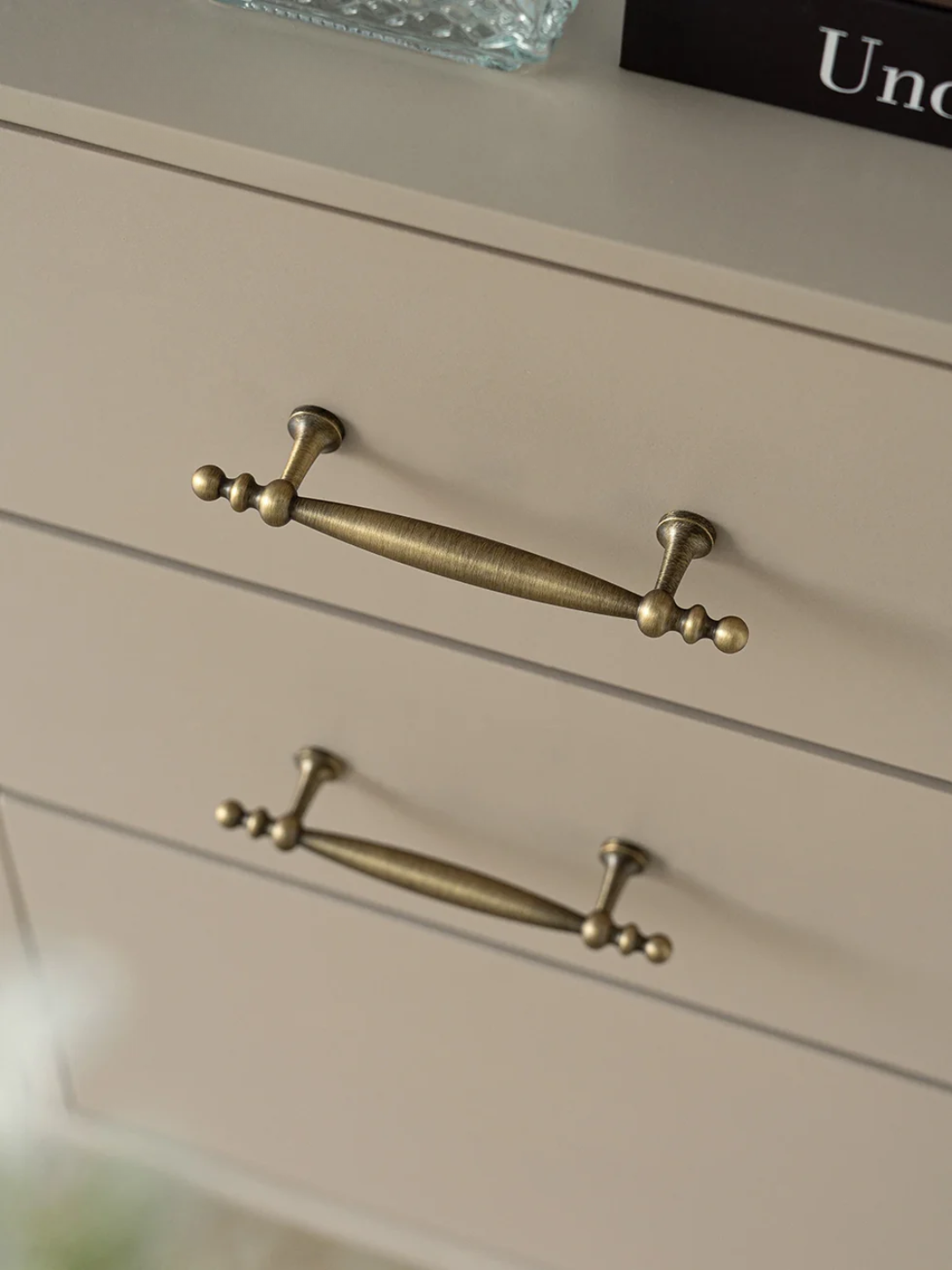 Close-up of a dresser with brass handles on a neutral background