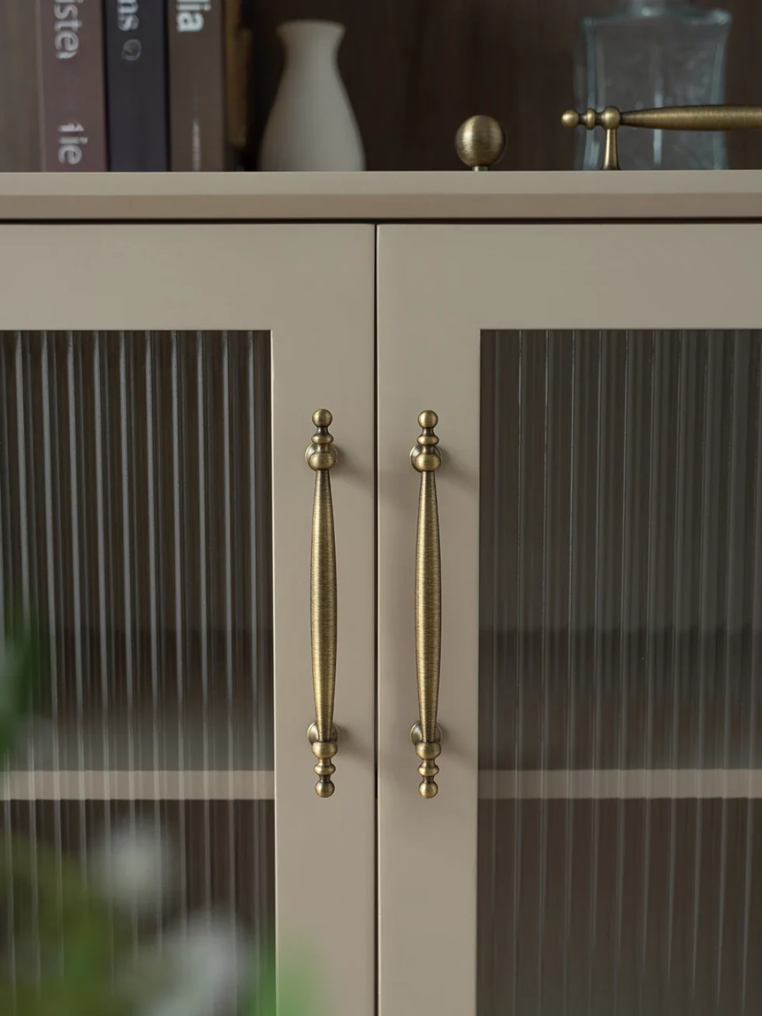 Cabinet with glass doors and brass handles in a blurred interior setting