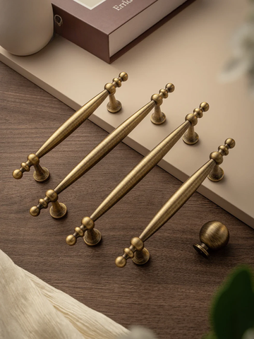 Set of gold cabinet handles on a wooden surface with a blurred background