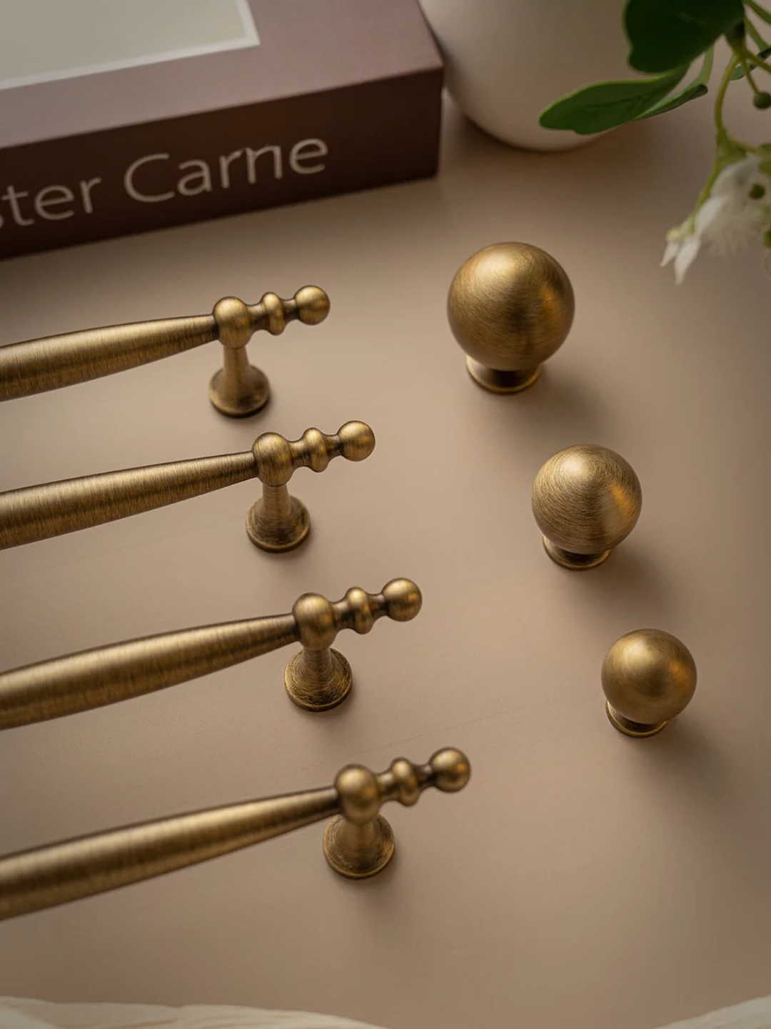 Collection of gold cabinet knobs on a neutral surface with 'Peter Carne' branding.