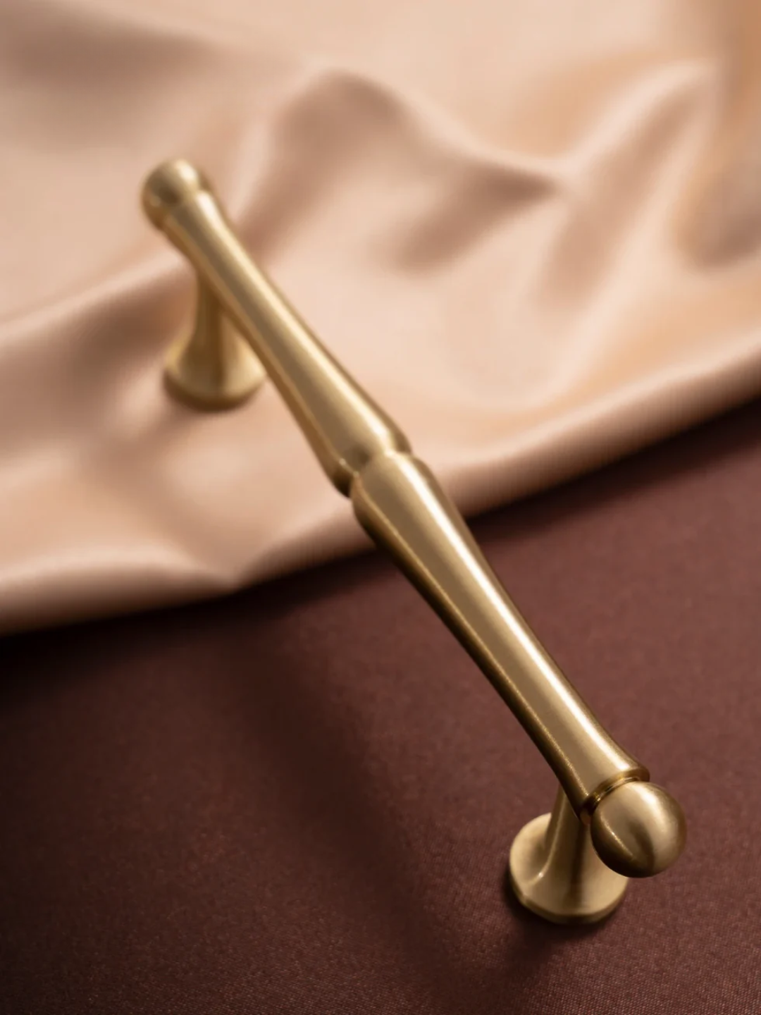 Gold handle on a brown surface with a beige fabric background