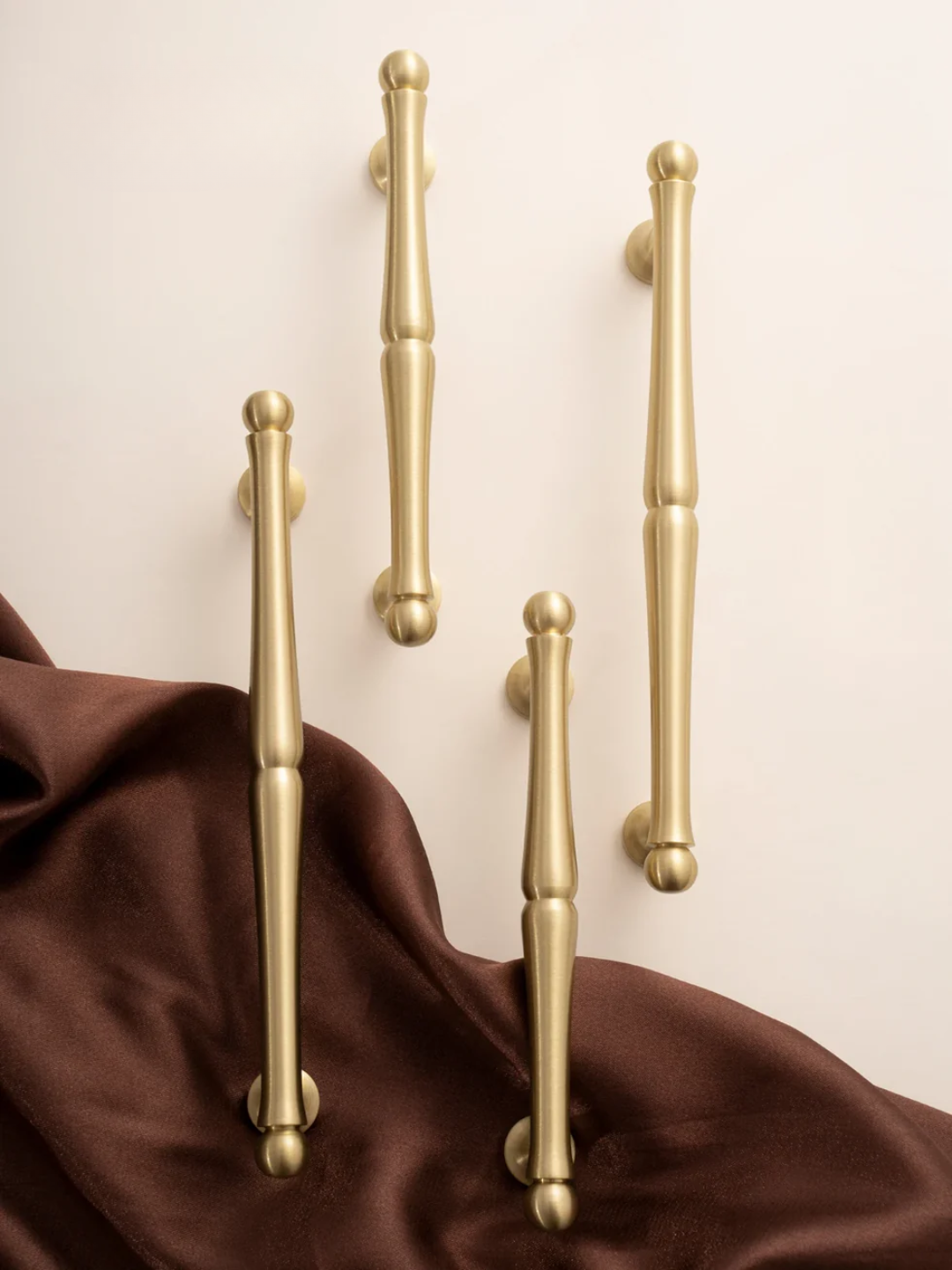 Set of gold handles on a beige background with brown fabric.