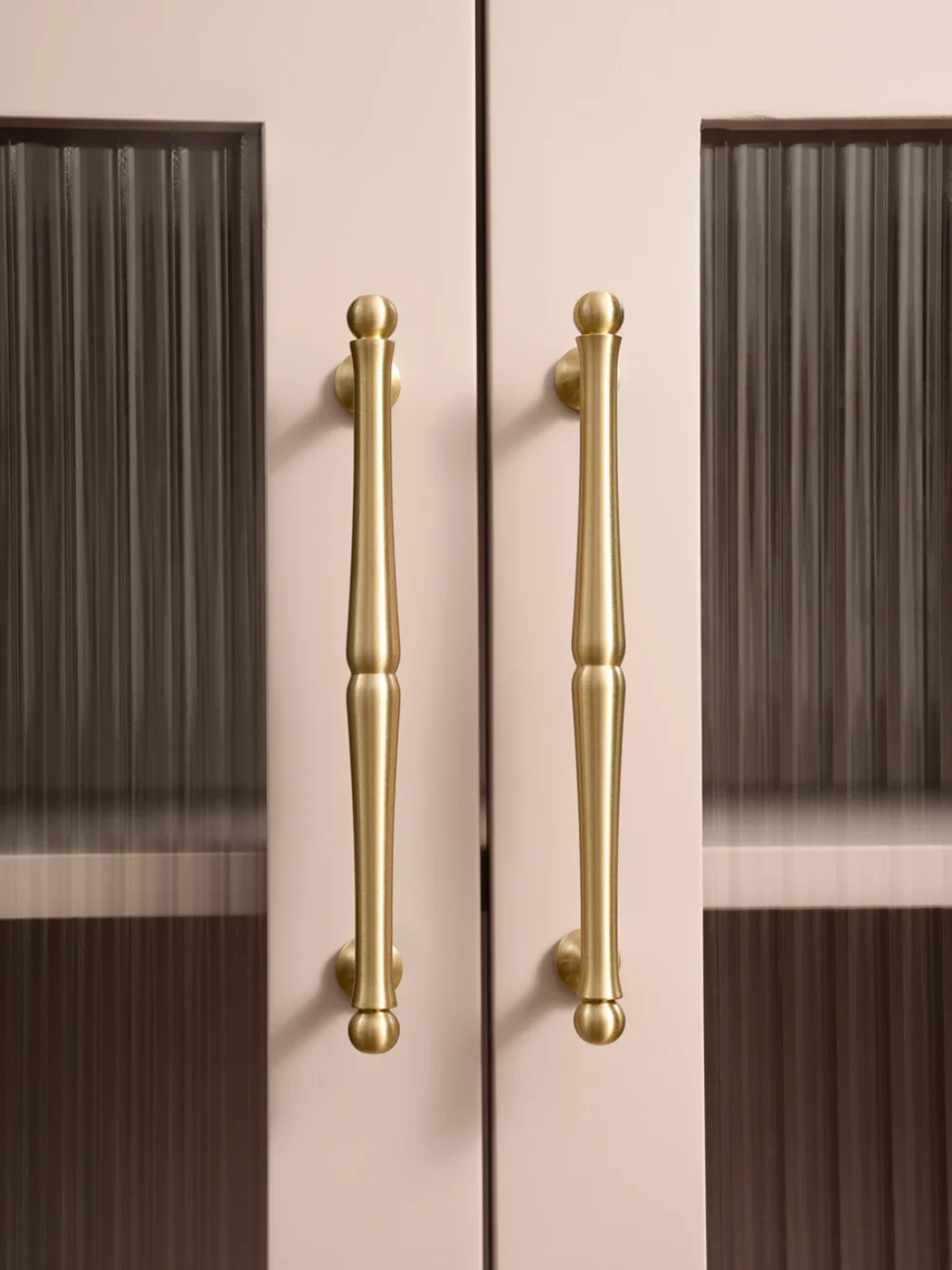 Gold cabinet handles on a pink and brown striped background