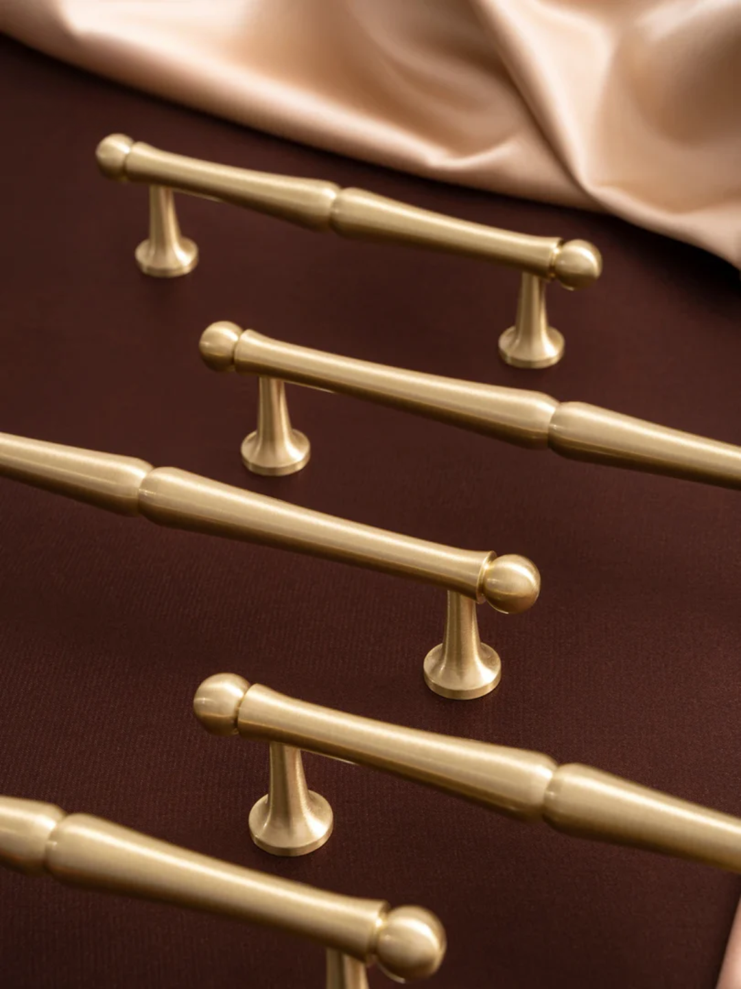 Set of gold towel bars on a brown surface with a white towel.