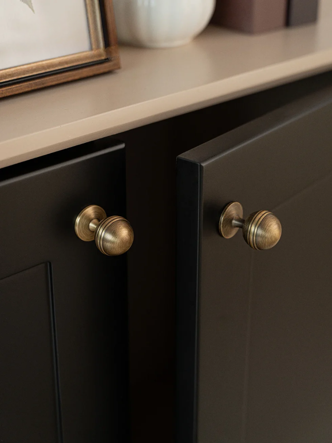 Close-up of dark wooden cabinet with brass knobs on a neutral background