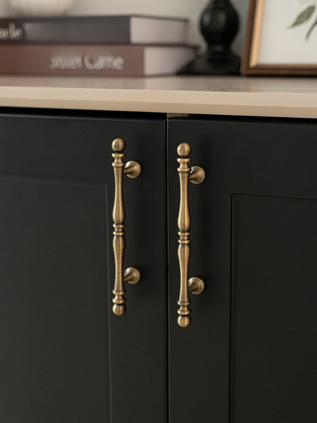 Black cabinet with gold handles on a neutral background