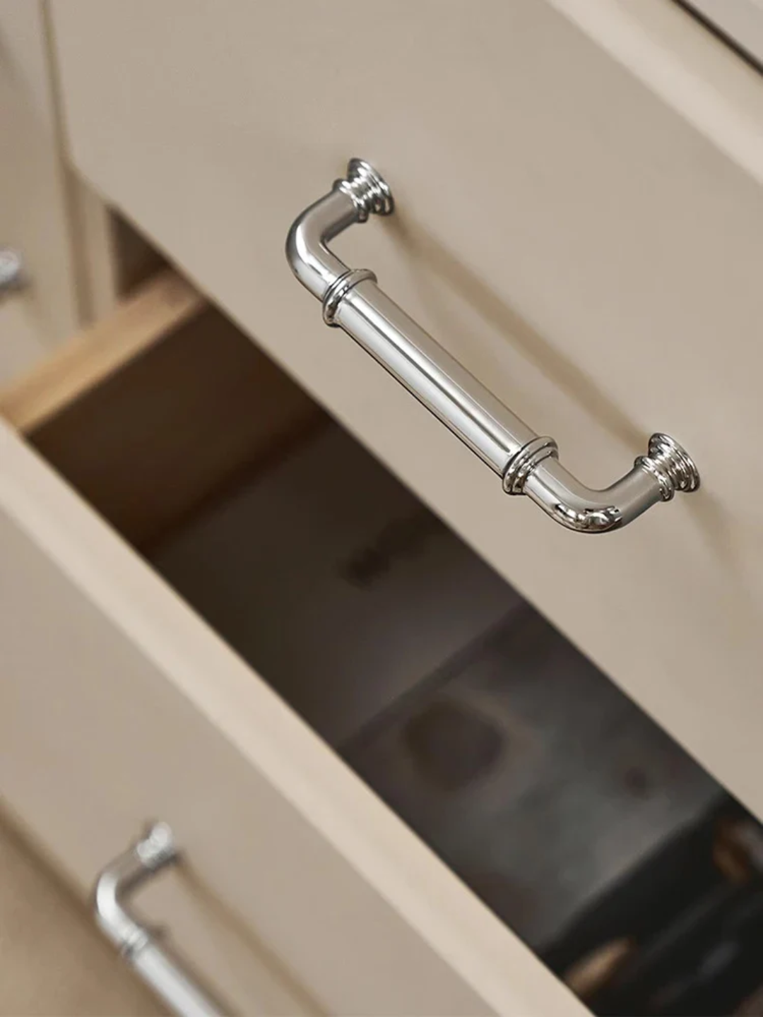 Close-up of a metallic cabinet handle on a beige cabinet.