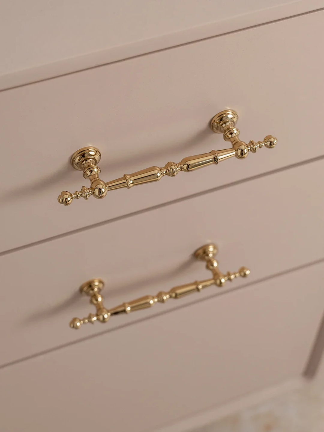 Gold cabinet handles on a light pink cabinet