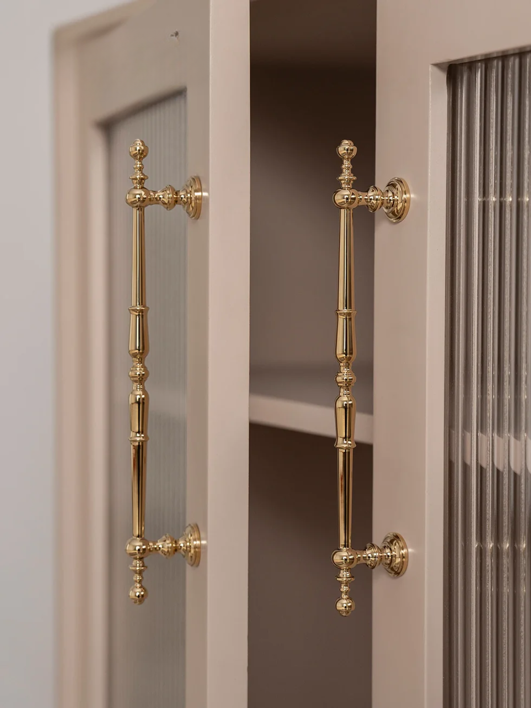 Gold cabinet handles on a door with a neutral background
