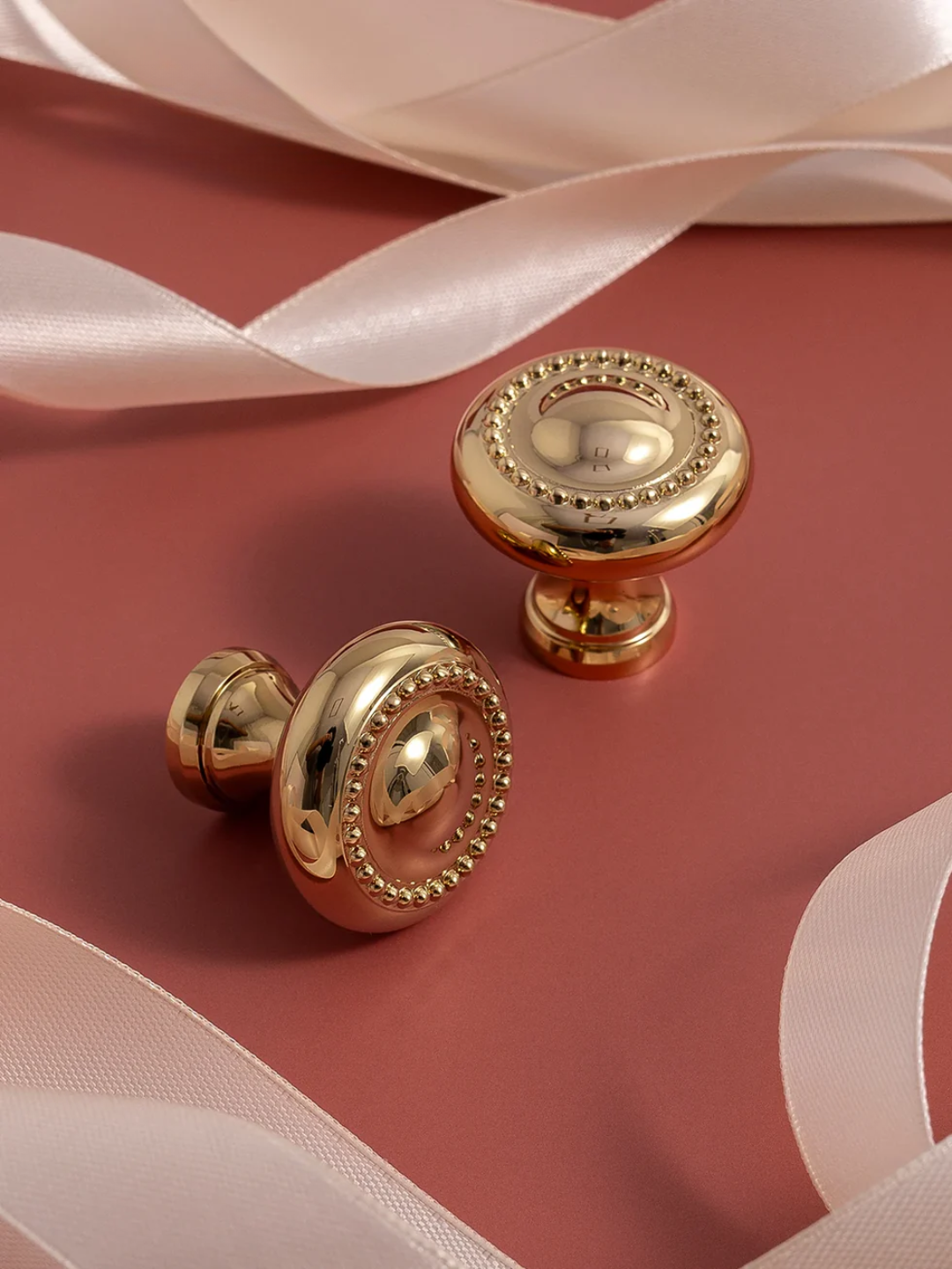 Gold door knobs on a pink surface with ribbons