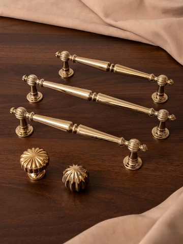 Set of gold cabinet handles and knobs on a wooden surface