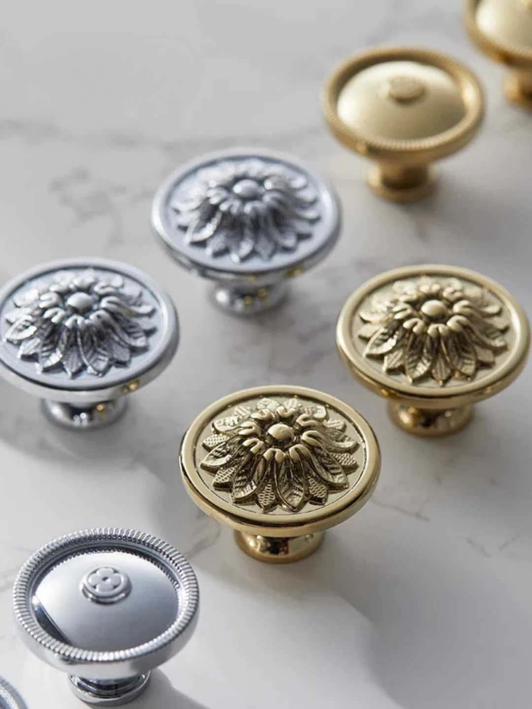 Decorative cabinet knobs in gold and silver on a light background