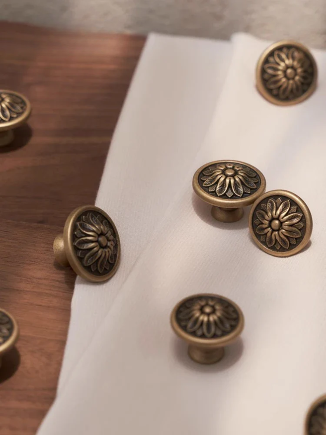 Bronze cabinet knobs on a white cloth with 'Santaya' branding.