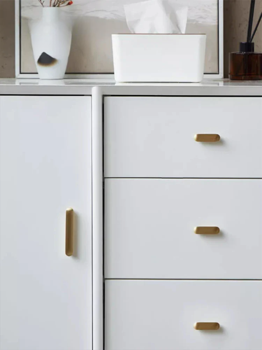 White cabinet with gold handles and decorative items on top