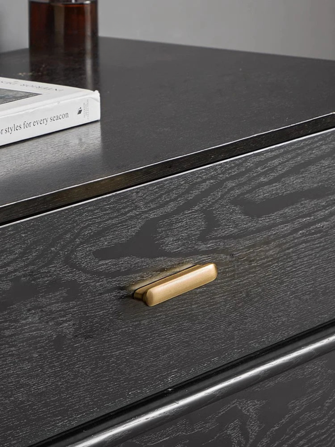 Dark wooden drawer with a gold handle on a matching surface.