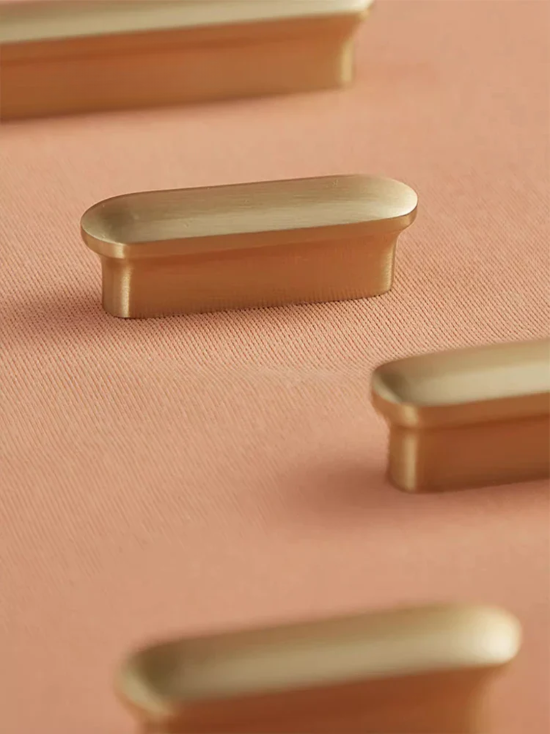 Brass cabinet knobs on a pink background