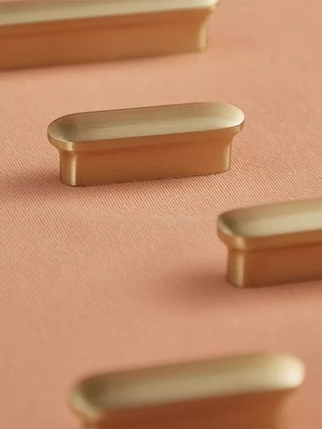Brass cabinet knobs on a pink background