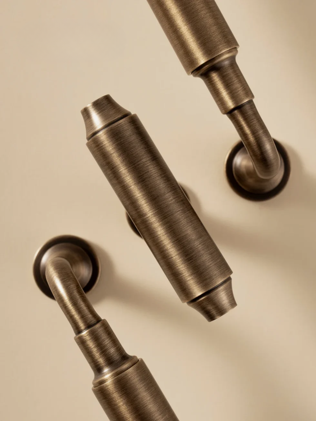 Three bronze door handles on a beige background