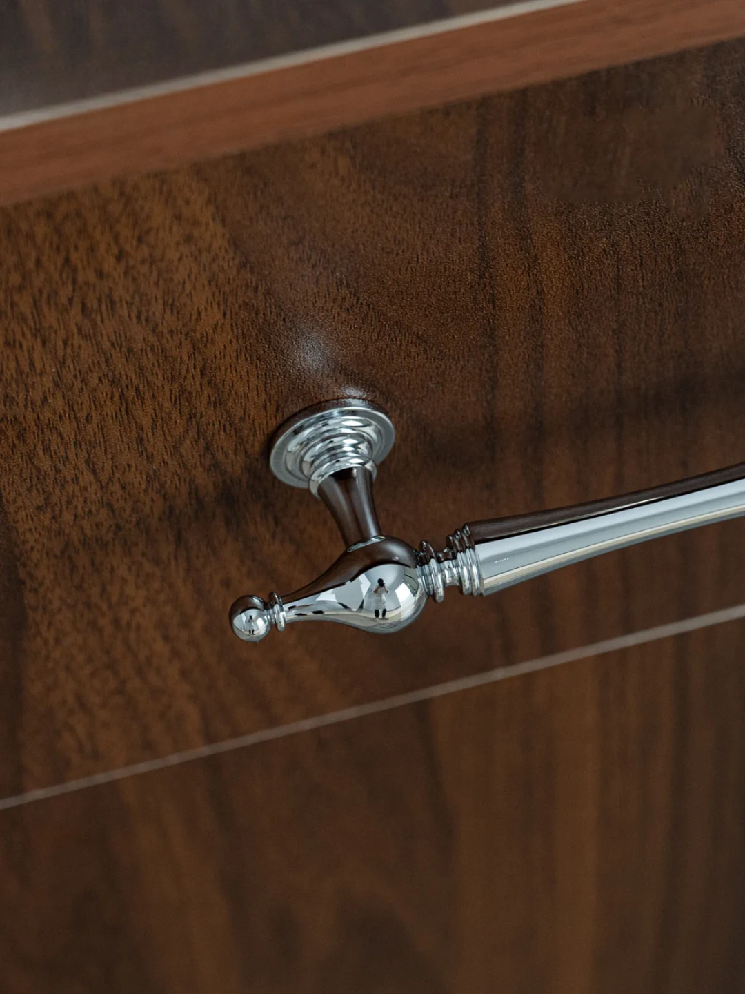 Close-up of a silver towel bar on a wooden surface