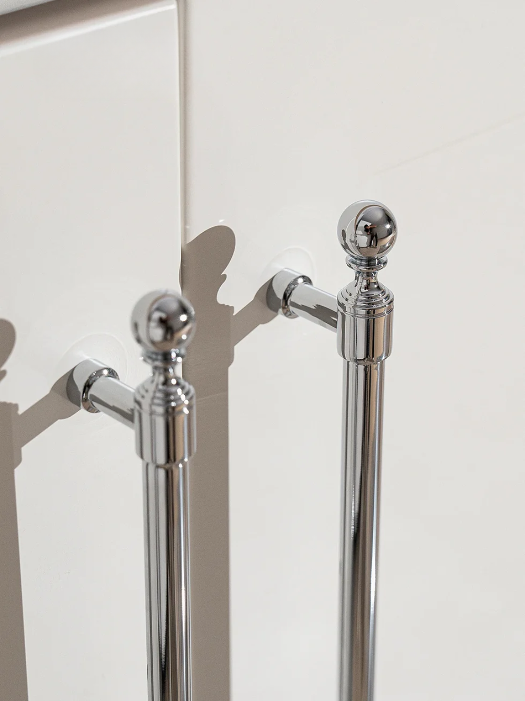 Chrome towel rail with decorative finials on a white wall