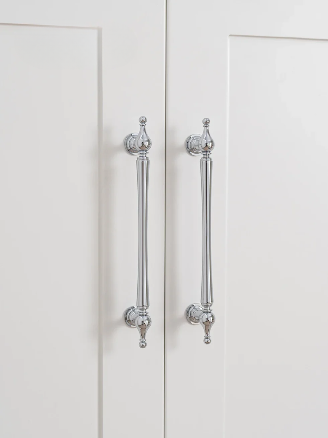 Close-up of a white cabinet with decorative silver handles